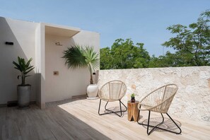 A rooftop terrace with two wicker chairs, a potted plant, and a stone wall. - LUX 4BR/4.5 Bath Villa - Private Pool & Hot Jacuzzi +Staff - BLUE DEER TULUM (Tulum)