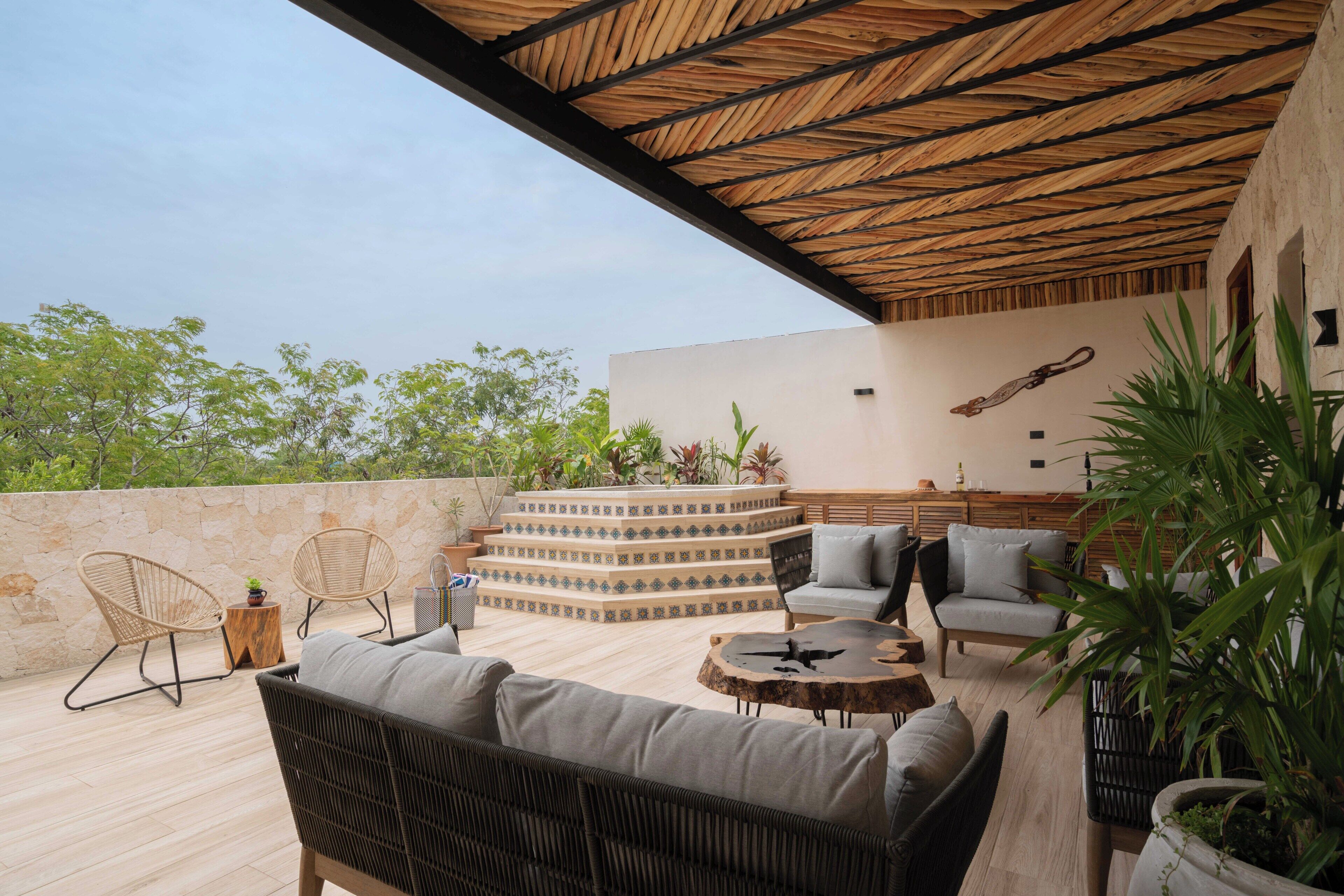 Una terrazza sul tetto con tetto di paglia, posti a sedere all'aperto e un muro decorativo.