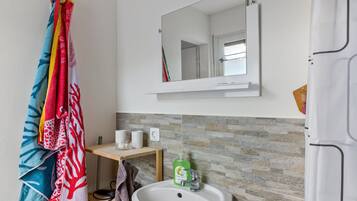 A bathroom with a white sink, a mirror above it, and a towel rack with colorful towels.