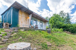A modern house with a large window, a wooden deck, and a stone staircase leading up to the entrance.