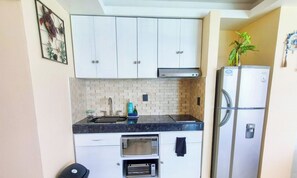 A compact kitchen with white cabinets, a built-in microwave, a stainless steel refrigerator, and a small sink. - Beachfront Studio w/ Balcony and Ocean View (Cancún)