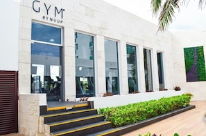 A gym with a white exterior, large windows, and a staircase leading to the entrance. - Beachfront Studio w/ Balcony and Ocean View (Cancún)