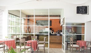 A cafe with a brick wall, a menu board, and tables with checkered tablecloths. - Beachfront Studio w/ Balcony and Ocean View (Cancún)