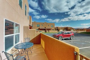 A hotel room with a balcony, a table, and chairs, and a view of the parking area and other buildings. - Spacious Townhouse with Shared Heated Pool, Tennis Courts, & Balcony Views (Moab)