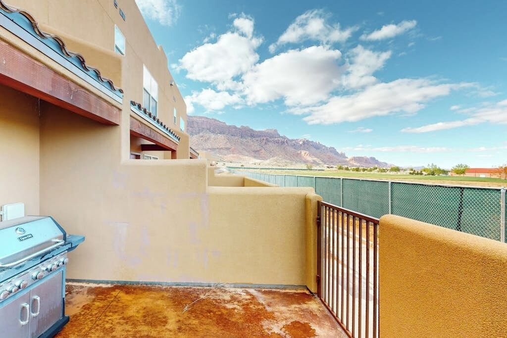 Ein Balkon mit Bergblick, einem Grill und einem eingezäunten Bereich.
