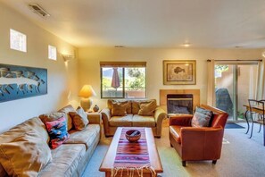 A living room with a sofa, armchairs, a coffee table, a fireplace, and a dining area. - Dog-Friendly Condo on Golf Course with Free WiFi & Seasonal Pool (Moab)