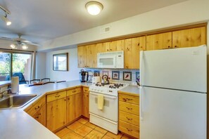 A kitchen with wooden cabinets, a white stove, a microwave, and a refrigerator. - Dog-Friendly Condo on Golf Course with Free WiFi & Seasonal Pool (Moab)