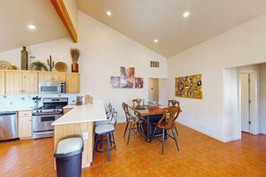 A spacious kitchen with a central island, wooden cabinets, a microwave, and a stove. - Spacious Moab Townhouse with Seasonal Pool and Hot Tub - Views and Hiking Nearby (Moab)