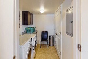 A laundry room with a washing machine, a chair, and a trash can. - Spacious Moab Condo with Pool Hot Tub and Mountain Views (Moab)