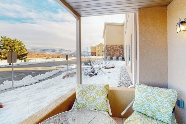 A covered outdoor seating area with a view of a snow-covered landscape and a building in the background. - Spacious Moab Condo with Pool Hot Tub and Mountain Views (Moab)