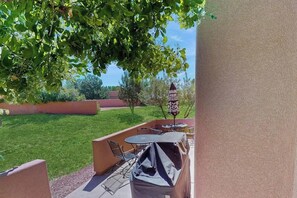 An outdoor patio with a barbecue grill, seating, and a decorative umbrella. - Condo with Beautiful Red Rock Vistas, Seasonal Pool, Fireplace, Grill, and WiFi (Moab)