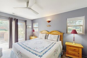 A bedroom with a bed, a ceiling fan, a nightstand with a lamp, and a window with curtains. - Condo with Beautiful Red Rock Vistas, Seasonal Pool, Fireplace, Grill, and WiFi (Moab)