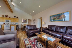 Ein geräumiger Wohnbereich mit Ledersofas, einem Holztisch und einer Küche im Hintergrund.