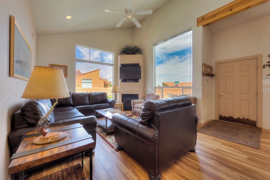 A spacious living room with leather sofas, a coffee table, a fireplace, and a television.