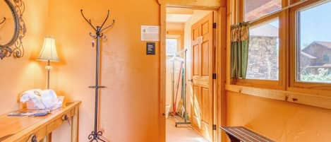 Un pasillo con un banco de madera, un perchero, una mesa con una lámpara y un espejo en la pared.