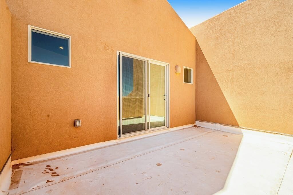 A building with a sloped roof, a sliding glass door, and a small window.