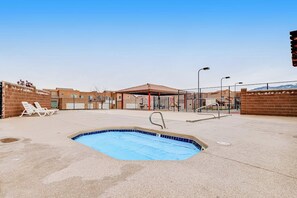 A swimming pool area with lounge chairs, a covered seating area, and a fenced pool. - Lovely Condo With Cozy Fireplace & Mountain Views - Great Location (Moab)