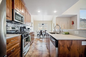 A modern kitchen with wooden cabinets, stainless steel appliances, and a central island. - Lovely Condo With Cozy Fireplace & Mountain Views - Great Location (Moab)