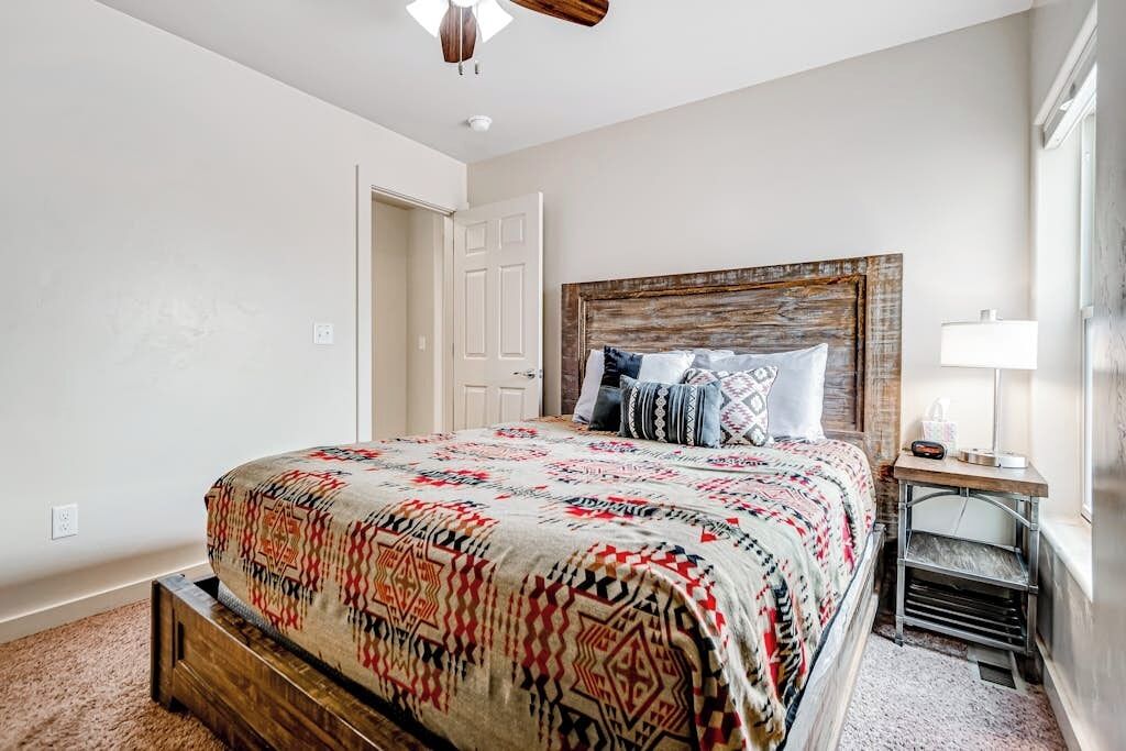 A bedroom with a bed, a nightstand, a lamp, and a door.