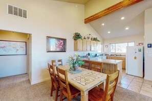 A spacious kitchen with wooden cabinets, a dining table with chairs, and a large island. - Family Friendly Home with Mountain View,  Great Locale, Seasonal Pool & Hot Tub (Moab)