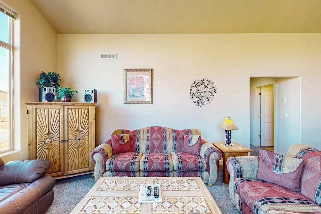 A living room with a patterned sofa, a coffee table, a cabinet, and a wall decoration.