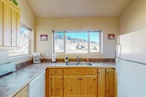 A kitchen with wooden cabinets, a sink, a coffee maker, and a refrigerator. - Family Friendly Home with Mountain View,  Great Locale, Seasonal Pool & Hot Tub (Moab)