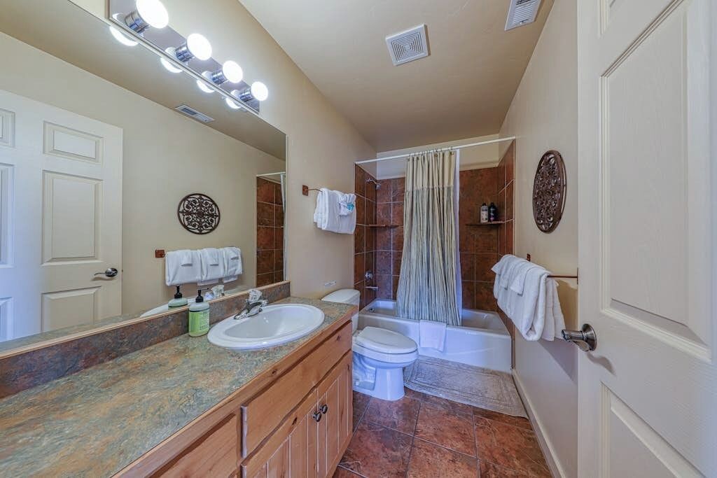 A bathroom with a sink, toilet, bathtub, and shower curtain.