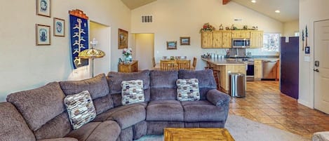 Una sala de estar con un sofá seccional, una mesa de centro y un comedor con mesa y sillas.