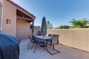 Eine Terrasse im Freien mit Tisch und Stühlen, einem überdachten Grill und einer Wand.