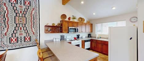 A kitchen with wooden cabinets, a microwave, stove, and a refrigerator.