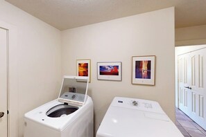 A laundry room with two white washing machines, a door, and three framed pictures on the wall. - Comfortable Home with Mountain Views and Shared Seasonal Hot Tub and Pool (Moab)