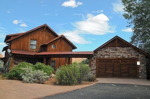 A two-story wooden house with a stone garage. - Luxury Home with Spectacular Views and Hot Tub - Walk to Golf Course (Moab)