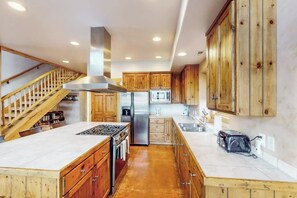 A modern kitchen with wooden cabinets, stainless steel appliances, and a built-in stove. - Luxury Home with Spectacular Views and Hot Tub - Walk to Golf Course (Moab)