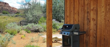 Une structure extérieure en bois, dotée d’un barbecue et d’un petit four.