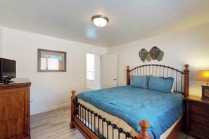A bedroom with a bed, a television, a door, and a wall-mounted decoration. - Spacious Townhome in a Great Location with Seasonal Shared Pool and Hot Tub (Moab)