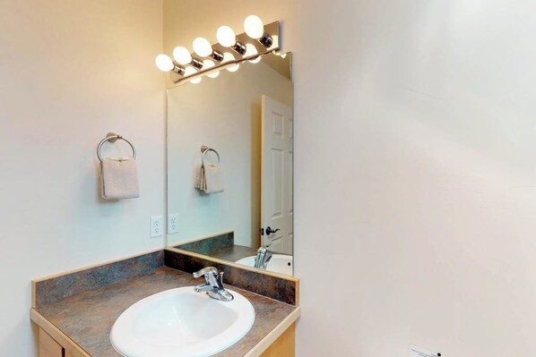 A bathroom with a sink, mirror, and lights above the mirror. - Spacious Townhome in a Great Location with Seasonal Shared Pool and Hot Tub (Moab)