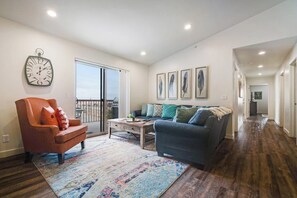 A spacious living room with a large window, a sofa, a chair, and a coffee table. - Cozy 3BR Moab Condo with Pool Hot Tub and Mountain Views near Arches (Moab)