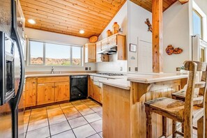 Eine Küche mit Holzausstattung, einem Geschirrspüler und einem Fenster mit Blick auf eine Wüstenlandschaft.