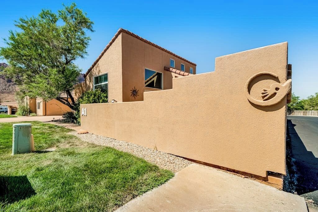 Un edificio con fachada de estuco, un ventanal grande y un emblema circular único en el lateral.