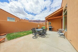 A patio with a table and chairs, a grill, and a view of the mountains. - Charming Condo with Mountain Views and Seasonal Pool & Hot Tub - Close to Town (Moab)