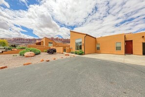 A modern building with a flat roof and a large window, surrounded by a landscaped area with rocks and shrubs. - Charming Condo with Mountain Views and Seasonal Pool & Hot Tub - Close to Town (Moab)