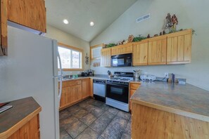 A kitchen with wooden cabinets, a microwave, a stove, and a dishwasher. - Charming Condo with Mountain Views and Seasonal Pool & Hot Tub - Close to Town (Moab)