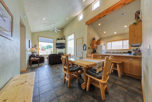 A spacious kitchen with wooden cabinets, a dining table, and chairs. - Charming Condo with Mountain Views and Seasonal Pool & Hot Tub - Close to Town (Moab)
