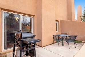 An outdoor patio with a grill, a table, and chairs. - Lovely Townhome with Shared Pool - Dog Friendly (Moab)