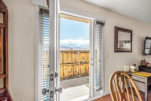 A room with a sliding glass door leading to a wooden fence, a desk with a chair, and a mirror on the wall. - Lovely Moab Home with Shared Pool Hot Tub and Stunning Desert Mountain Views (Moab)