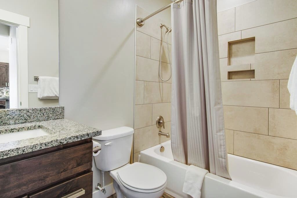 Een badkamer met toilet, wastafel, bad en douchegordijn.
