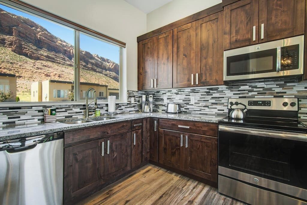 Una cocina moderna con armarios de madera, electrodomésticos de acero inoxidable y vistas a un paisaje montañoso.