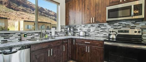 Una cocina moderna con armarios de madera, electrodomésticos de acero inoxidable y vistas a un paisaje montañoso.