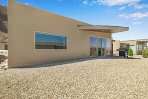 A modern building with a flat facade, large windows, and a gravel driveway. - Comfortable Moab Condo with Patio and Views - Close to Arches and Downtown (Moab)
