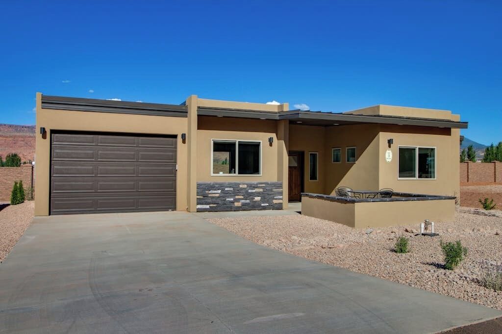 A two-story house with a garage, a stone accent wall, and a patio with outdoor furniture.